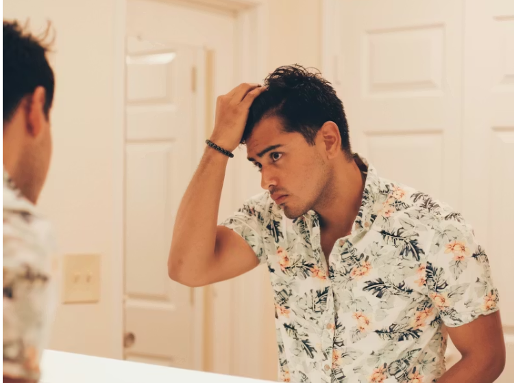 거울 앞에서 헤어라인을 살피는 젊은 남성의 모습