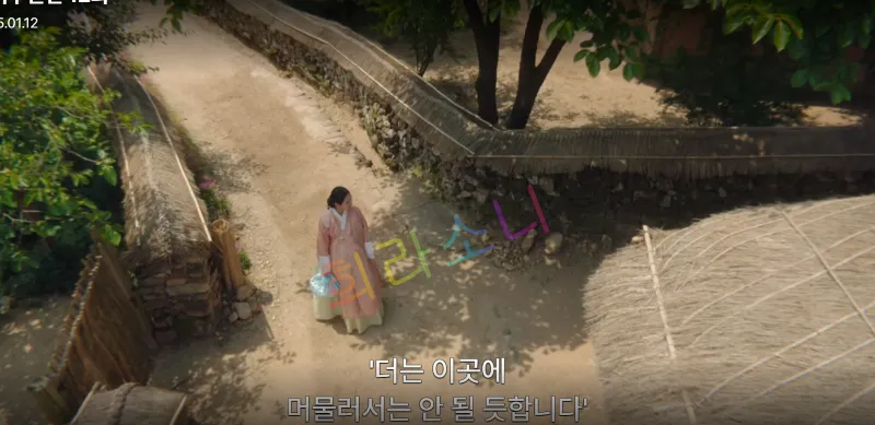 미령이 외딴 길을 혼자 걷고 있다. 배경에는 초가집 울타리와 나무가 보인다. 자막 