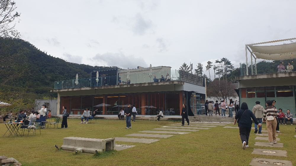정원에 테이블과 의자 있다. 넓은 정원에 고객들이 많다.