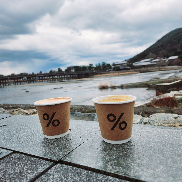 강변에 두 잔의 커피가 놓여 있다. 커피 잔에 있는 %문구가 눈에 들어 온다.