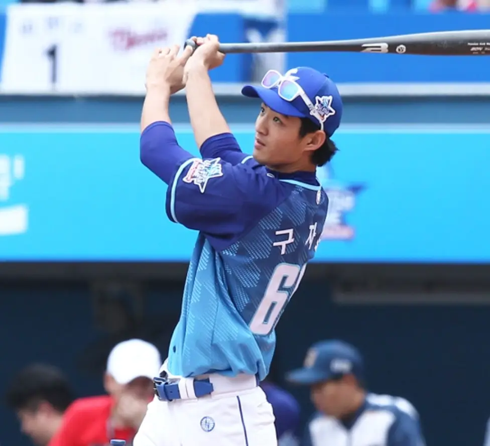 야구 구장 파란 유니폼에 흰 바지를 입은 선수가 방망이를 휘두르는 모습