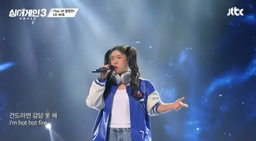 싱어게인3-
붉은 무대조명 청바지야 파란잠바를 입고 머리를 양갈래로 묵고 검정색 마이크를 들고 노래하는 46호가수의 왼쪽 얼굴