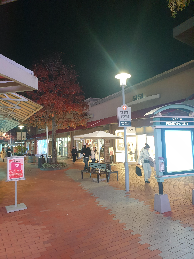 어두운 밤 조명이 밝게 켜있는 매장들. 손에 쇼핑백을 들고 다니는 사람들