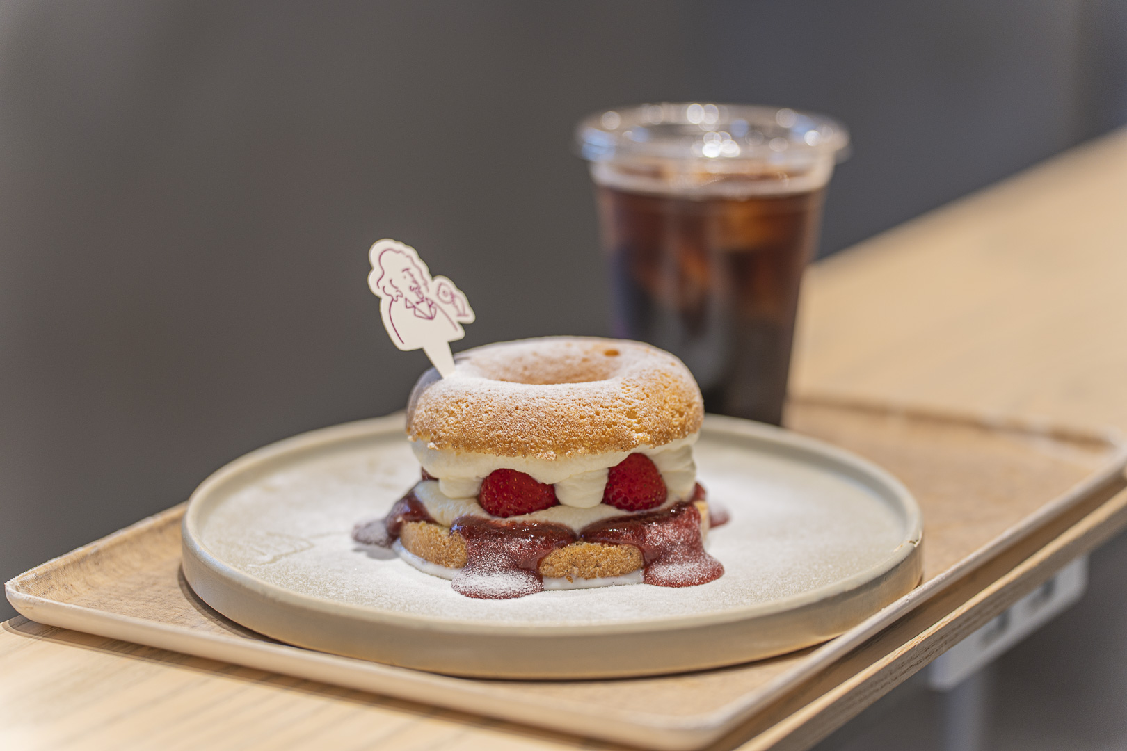 koe donuts Kyoto: a doughnut filled with strawberries and cream, with iced coffee behind.