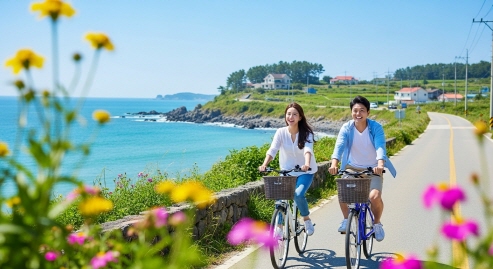 커플이 자전거를 타고 해안 도로를 달리는 모습