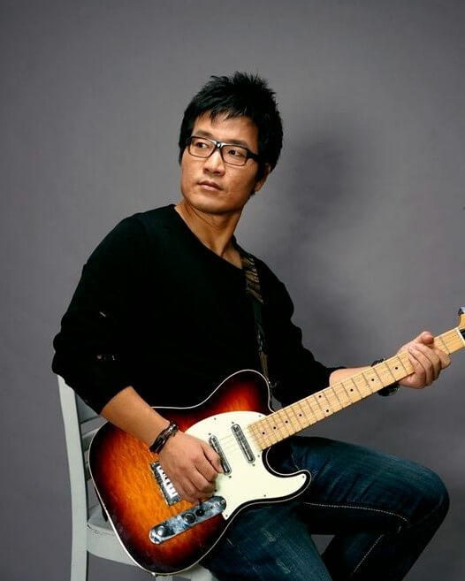 유해준이-일렉기타를-들고-의자에-앉아-오른쪽을-응시하는-사진