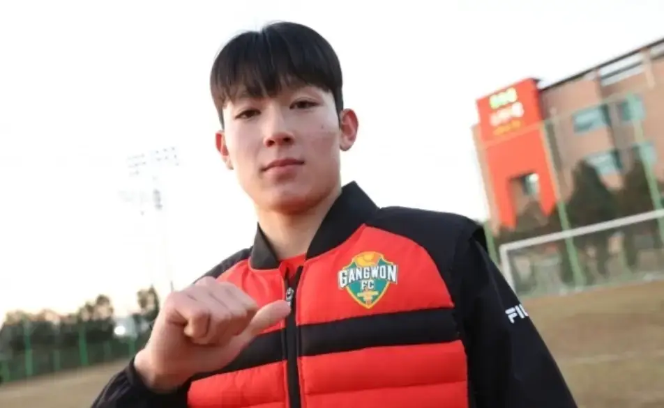 야외 운동장 검은색과 붉은색이 섞인 점퍼를 입고 오른손 엄지손가락으로 자신을 가리키는 양민혁