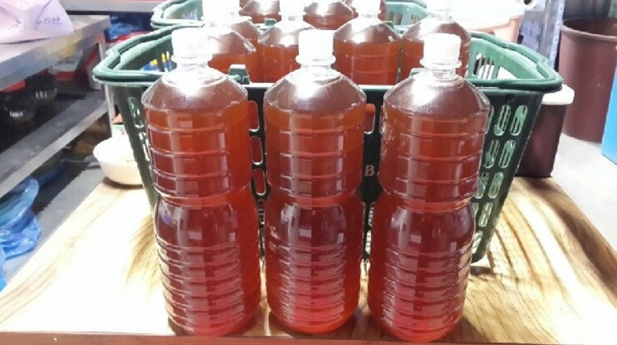 나무 테이블 위에 초록색 바구니를 두고 그 안에 매실엑기스를 담은 투명한 플라스틱 통을 어러 개 담아두고 그 앞에는 매실엑기스를 담은 투명한 플라스틱 통 3개를 나란히 두고 찍은 사진