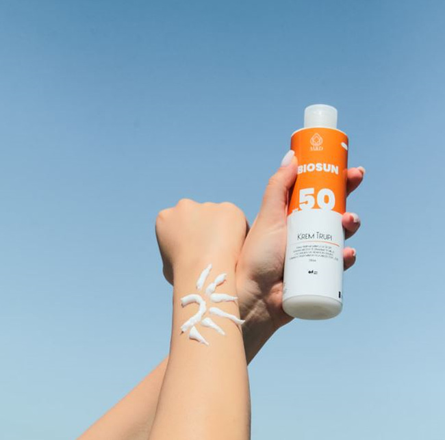 손에 자외선 차단제를 바르고 용기를 들고 있는 사진