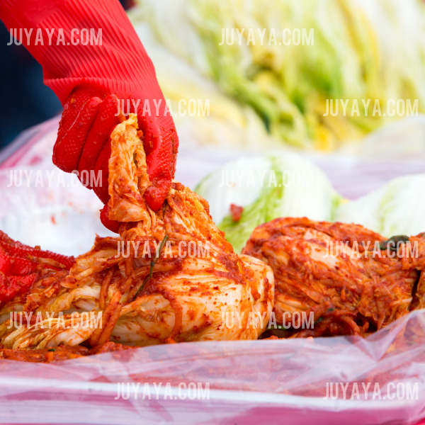치 완성 후 김장을 마무리하는 모습 - 빨간 고무장갑을 착용한 사람이 김장김치를 손으로 정리하는 장면. 배추가 붉은 양념으로 잘 버무려진 모습이 돋보임.