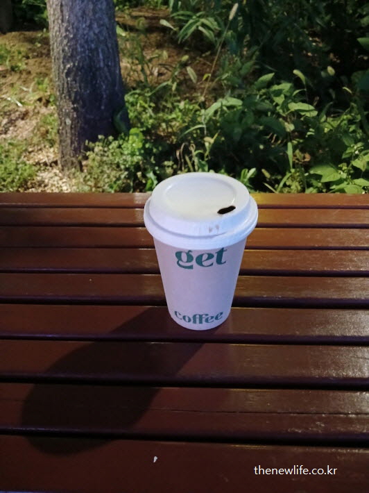 야외 벤치 위에 놓인 테이크아웃 블랙커피 컵, 조용한 사색의 순간