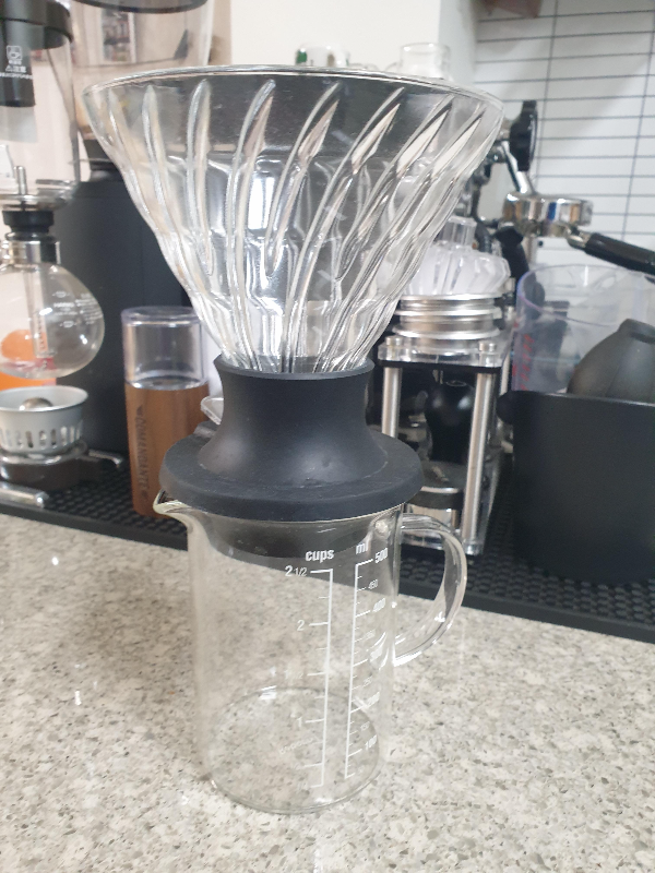 테이블 위에 하리오 스위치가 놓여있다. 뒤에는 각종 커피 도구들이 보인다.