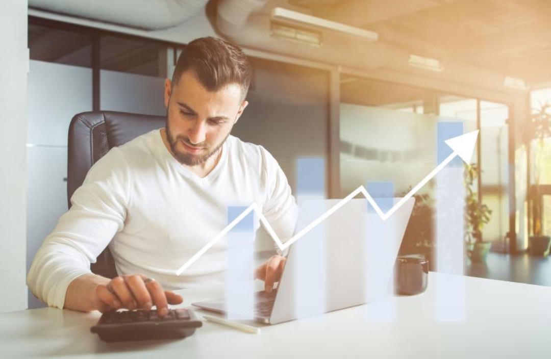 한 남성이 계산기를 두드리고 있고 상승하는 그래프가 그려져 있다.