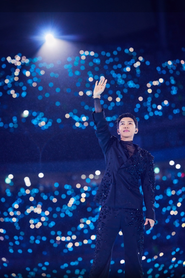 임영웅 콘서트 영화의 한 장면. 푸른 조명 아래 임영웅이 관객들을 향해 손을 뻗어 인사하고 있다.