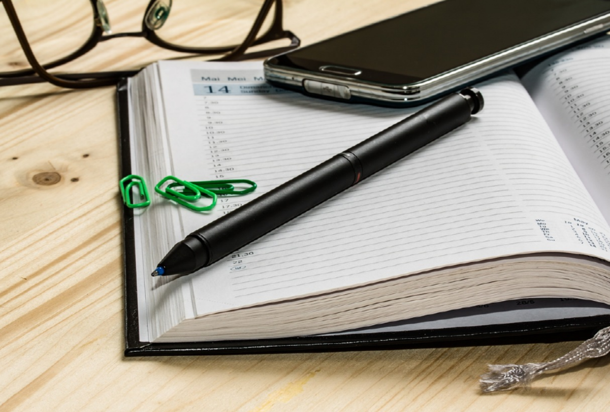 노트와 연필과 안경, 휴대폰이 있는 사진