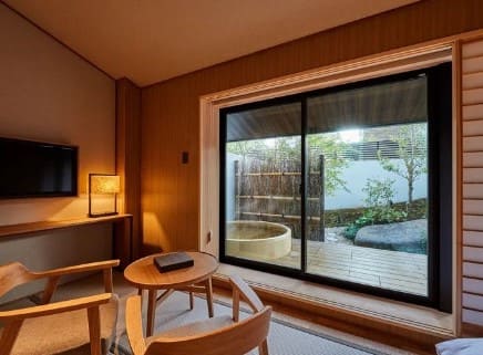 테이블과 의자 그리고 창밖으로 나무로 만든 욕조가 보인다.