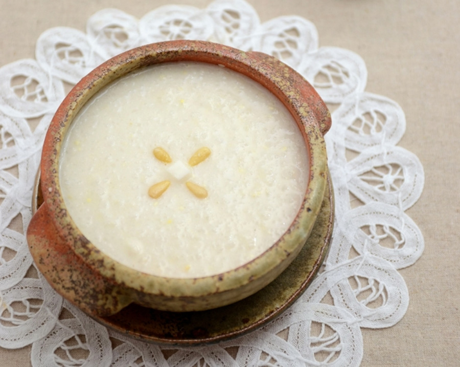 야생에서 채취를 한 마를 쌀과 함께 갈아서 만든 마죽을 동그란 그릇에 가득 담은 후에 잣 4개를 놓아둔 것을 찍은 사진