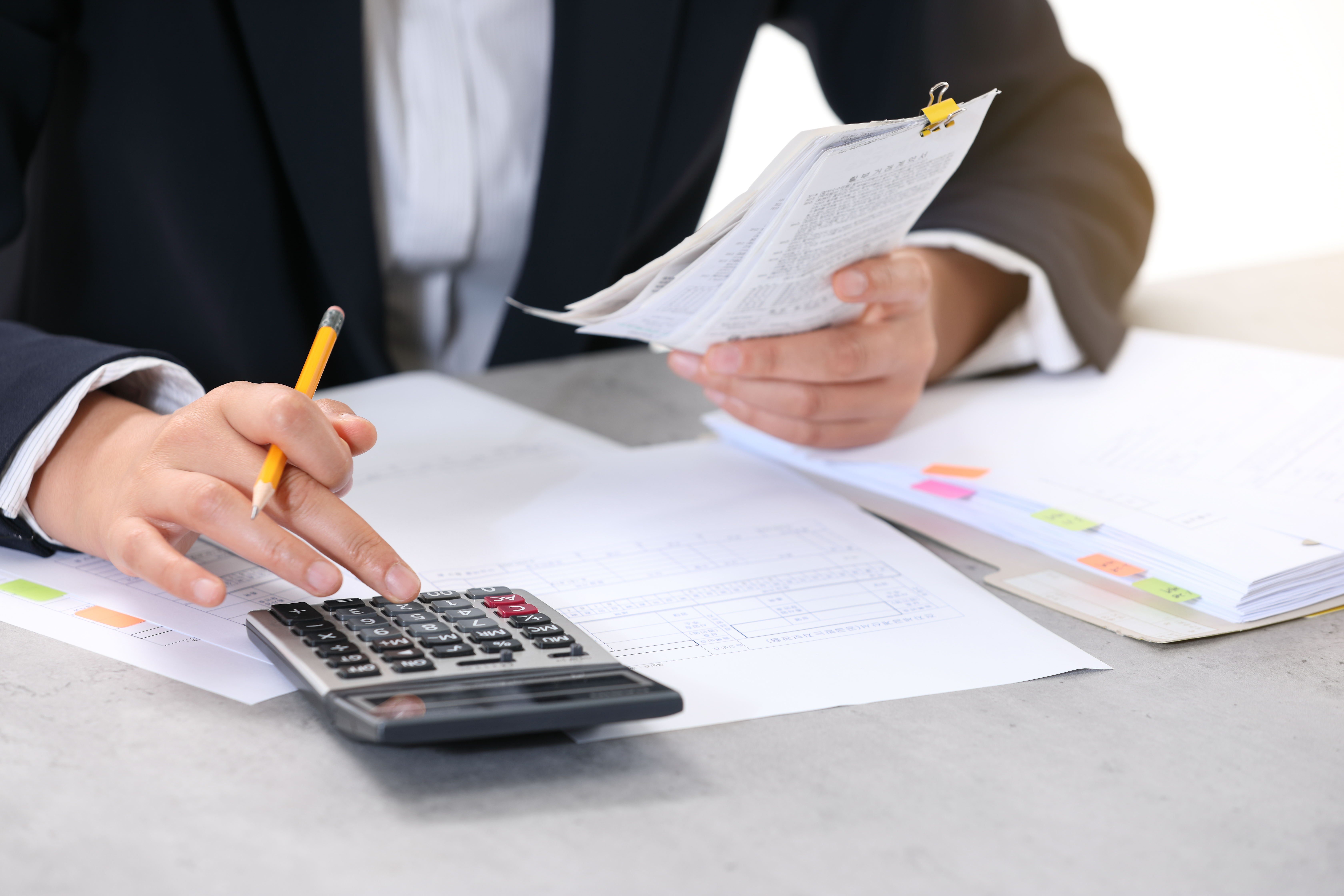 사업자가 부가세 신고를 위해 계산기와 영수증, 세금 서류를 검토하는 모습