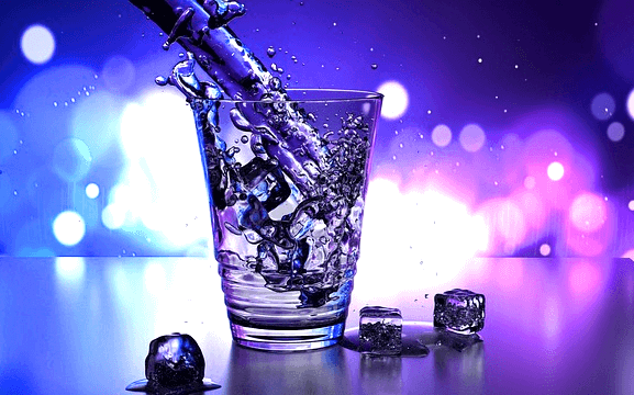 투명한 유리컵에 생수를 담고 있다. 컵 안에는 얼음조각이 있고 바닥에도 얼음조각이 있다.
