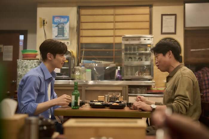 영화 소주전쟁에서 두 남성이 식당에서 소주를 마시며 대화하는 장면