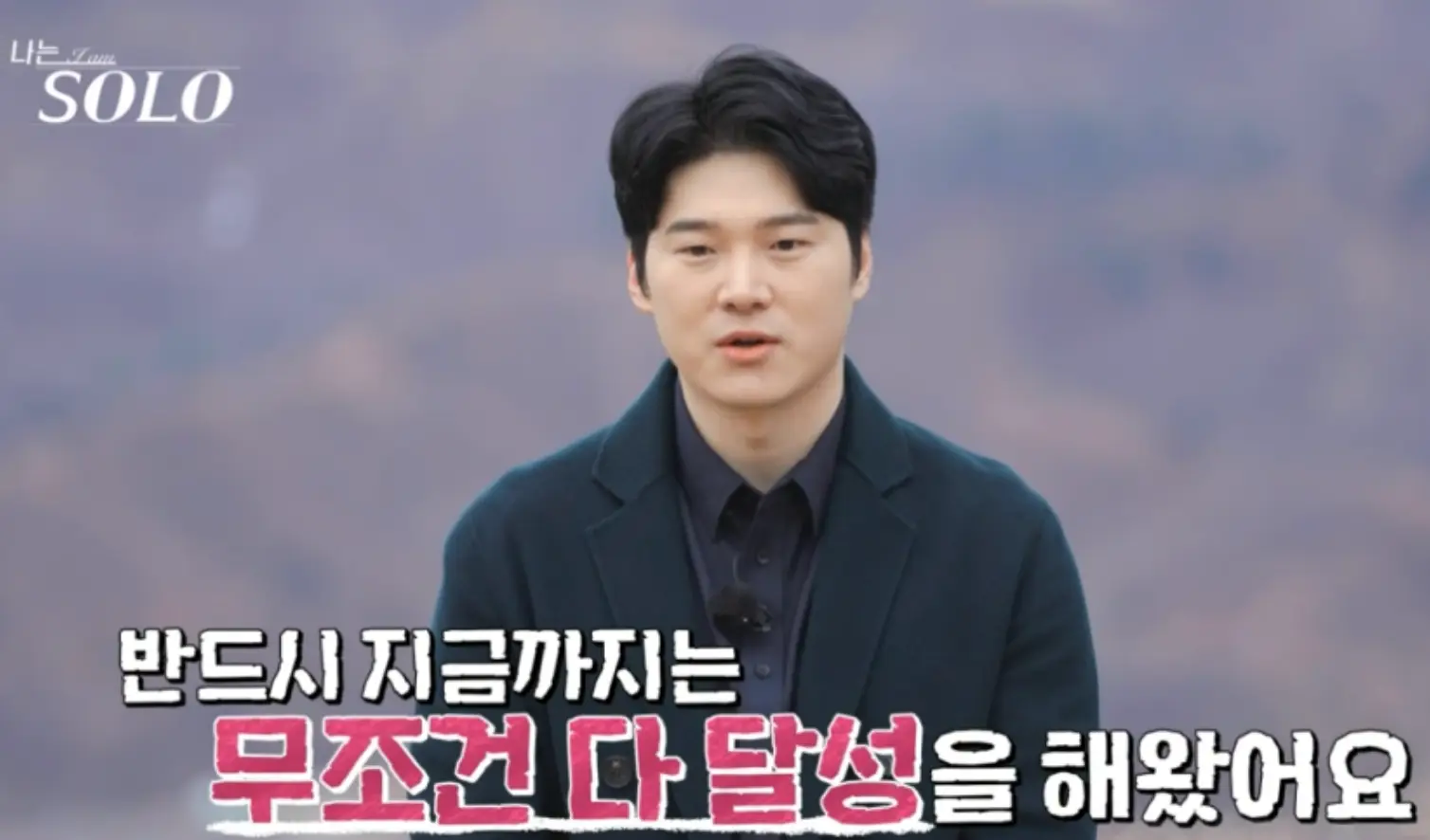 나는 솔로-숲배경 검은 코트를 입고 얘기하는 영식 아래 흰색과 분홍색이 섞인 글씨 반드시 지금까지는 무조건 다 달성을 해왔어요