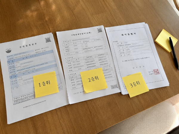초등학교 돌봄교실 신청을 위해 주민등록등본과 가족관계증명서 등 서류를 순위별로 정리하는 모습