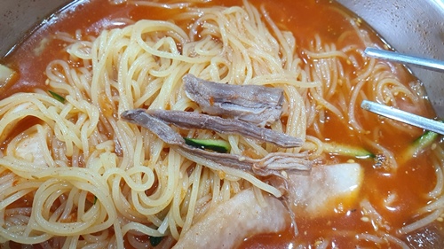 밀면 위에 놓여진 찢어놓은 삶은고기