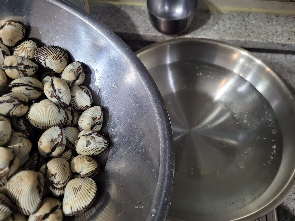 끓는 물에 꼬막을 넣으려는 사진