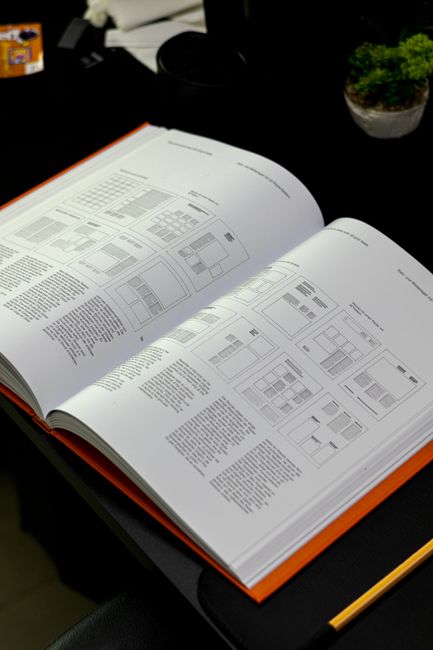 편집 디자인을 보여주는 디자인 레이아웃과 그리드 시스템이 적용된 책이 작업대 위에 펼쳐져 있습니다.