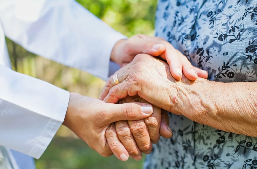 젊은 사람이 노인의 두 손을 잡고 있는 모습