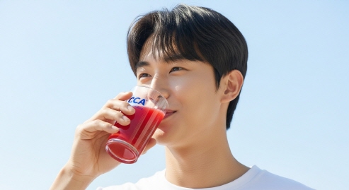 밝은 자연광 아래 CCA 주스를 한 모금 마시는 모습