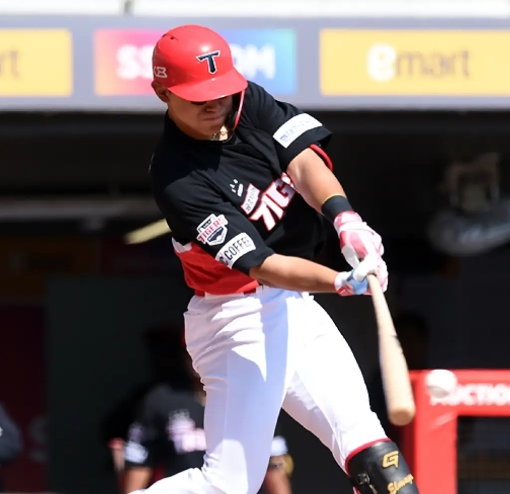 붉은색 헬맷 검은색과 붉은색이 섞인 상의 유니폼 흰바지를 입고 두손으로나무배트를 든채 공을 치는 김도영