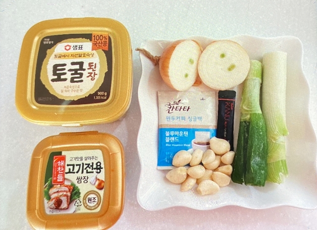 토굴 왼장과 고기전용 쌈장 그리고 접시위에 올려져있는 양파, 대파, 커피가루, 통마늘
