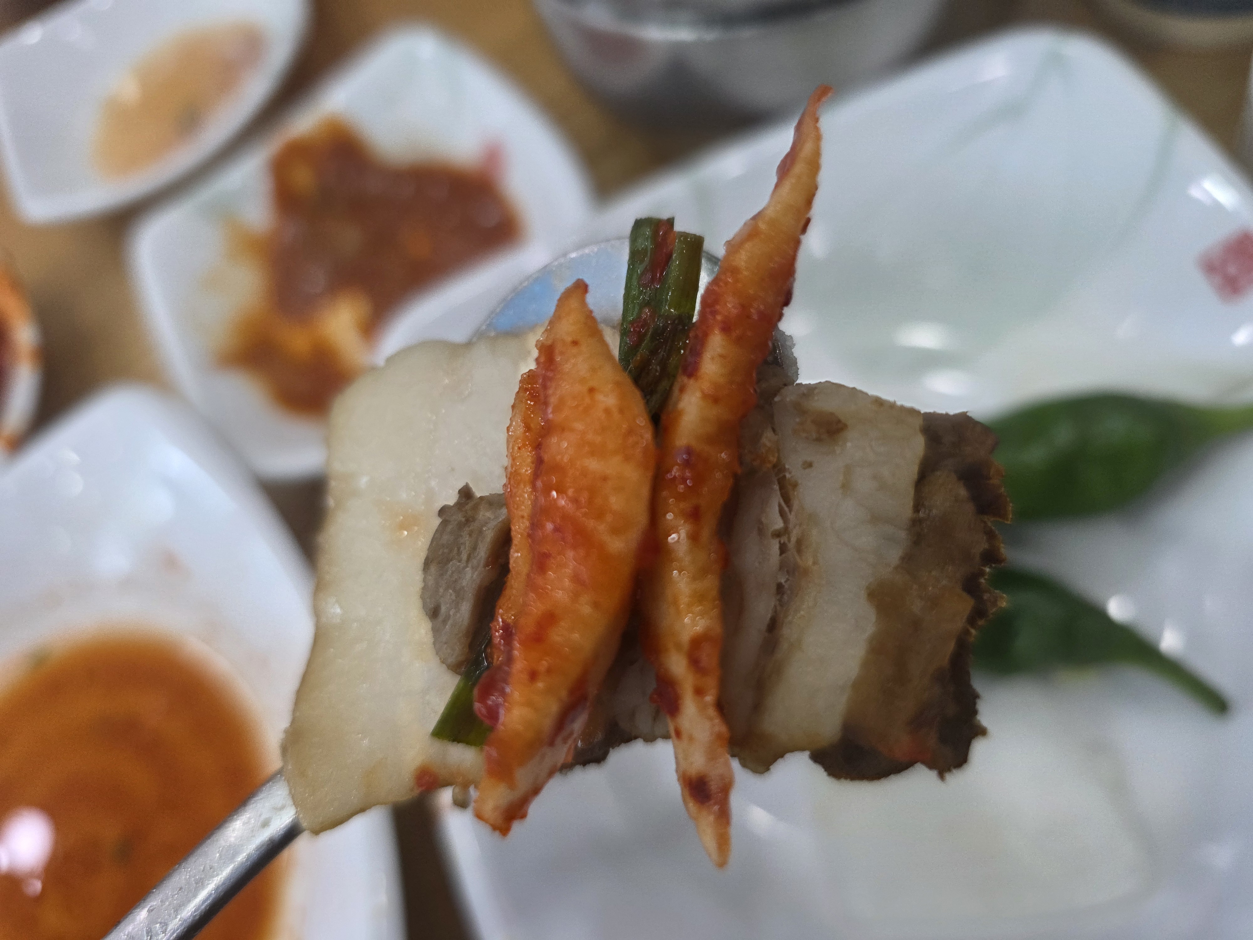 삶은 보쌈 고기에 김치와 부추를 올려 먹는 모습