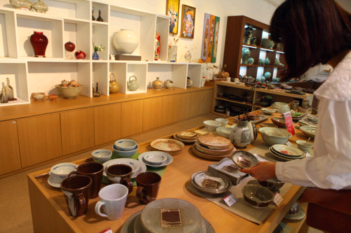 한여인이 도자기 그릇들을 보고 있다.