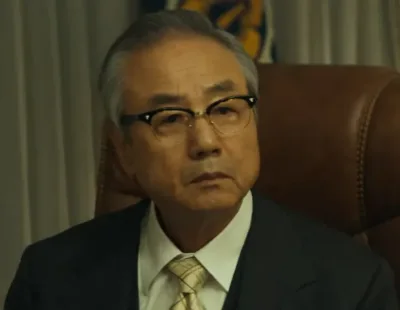 백발에 안경을 쓰고 앉아 있는 영화 서울의 봄에서 최한규를 연기하는 정동환