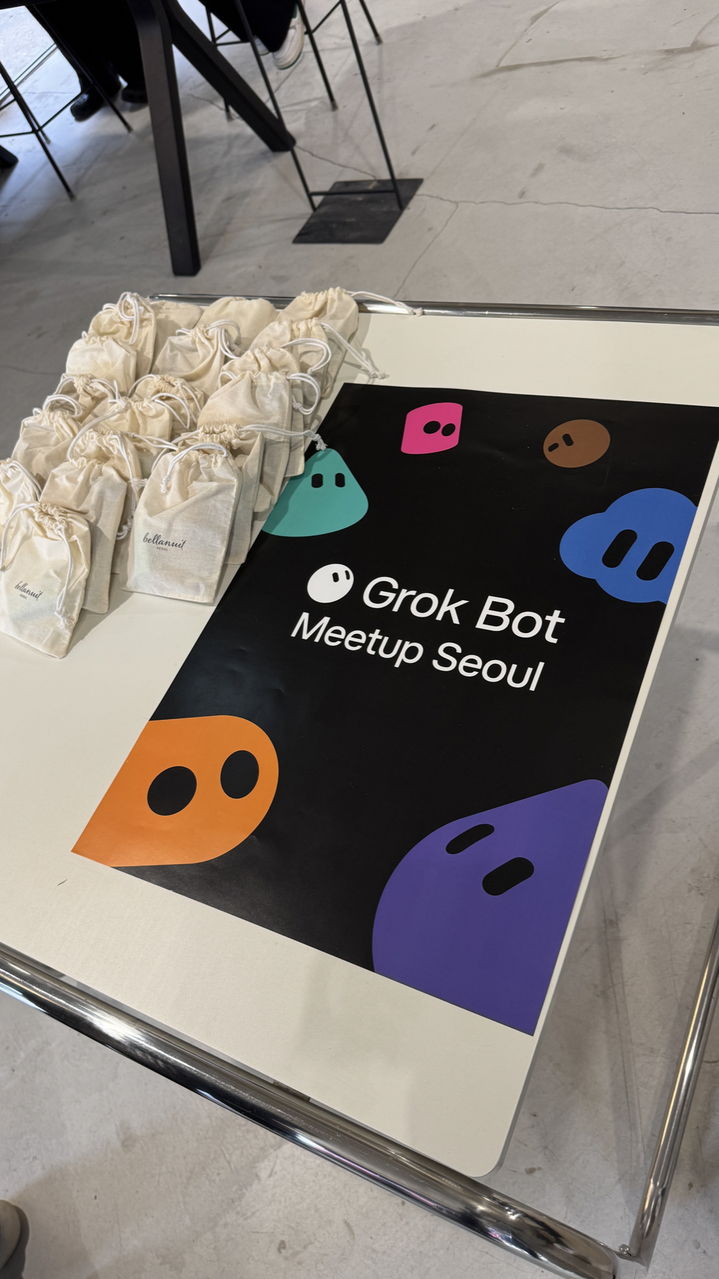 Grok Bot Meetup Seoul 포스터와 여러 천 파우치가 놓인 행사 테이블