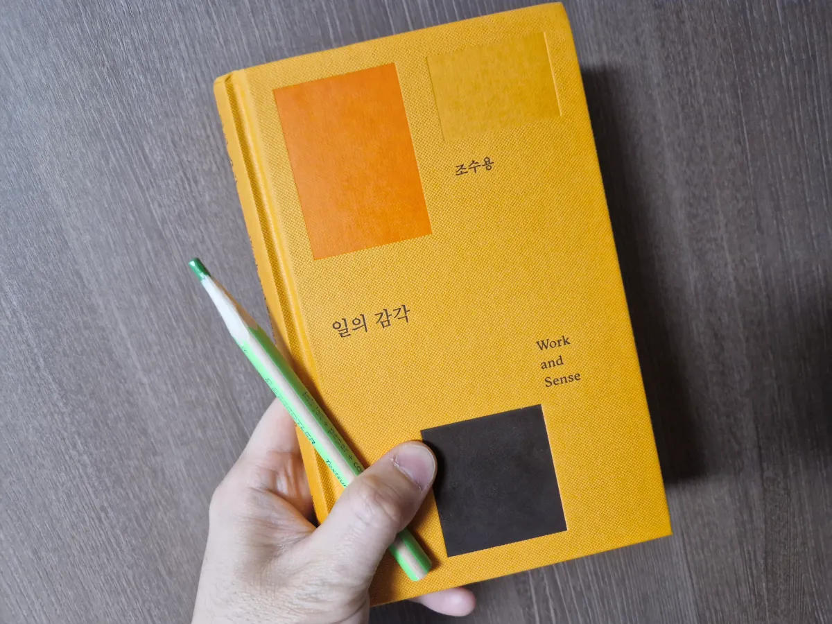 주황색-일의감각-책과-초록색-연필을-들고있는-손