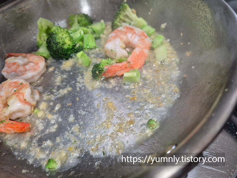 Close-up of adding pasta water to the pan to prevent minced garlic from burning.