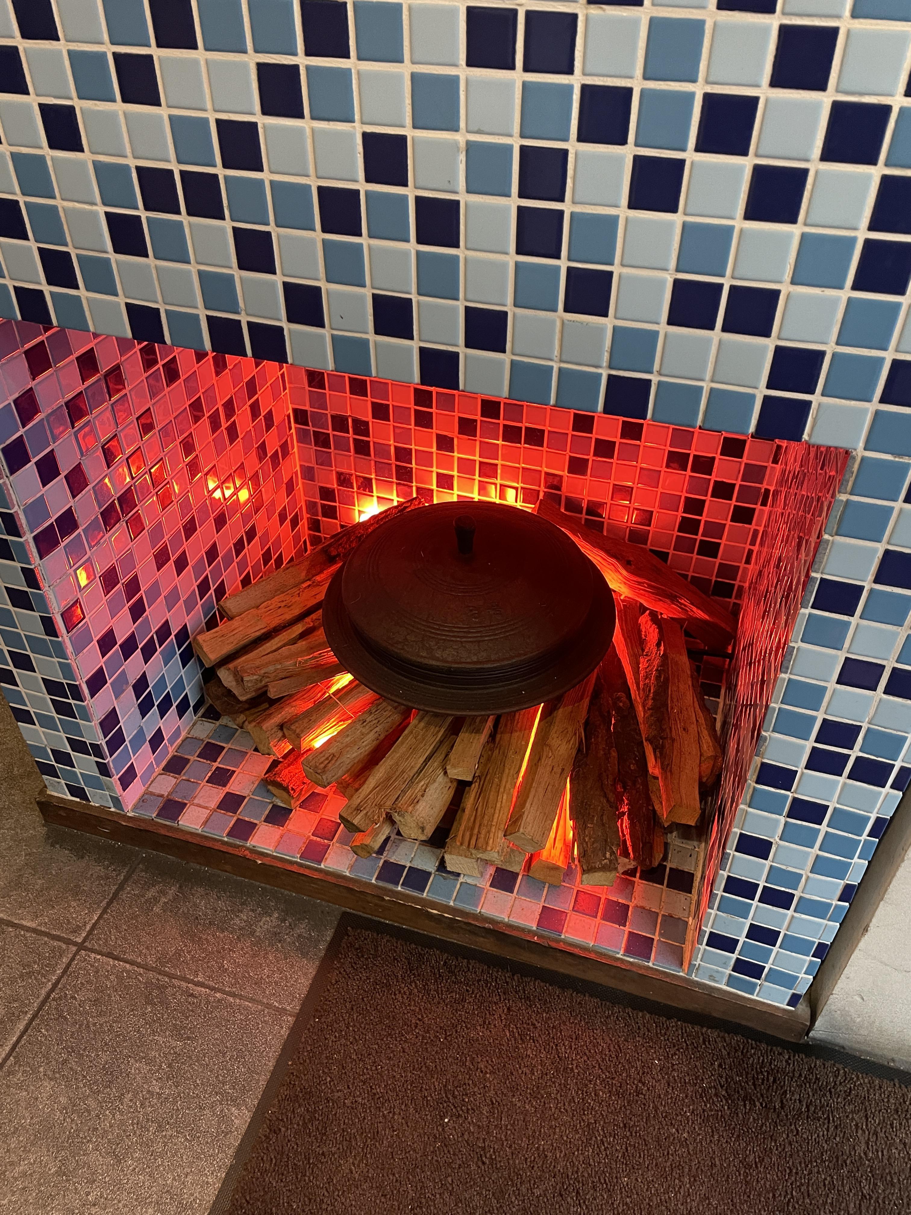 성수옥아궁지 부천상동점 카운터 아래 장작과 가마솥이 있는 사진. 장작들 아래 전구를 활용해서 꼭 불이 붙어있는 모양을 하고 있다.
