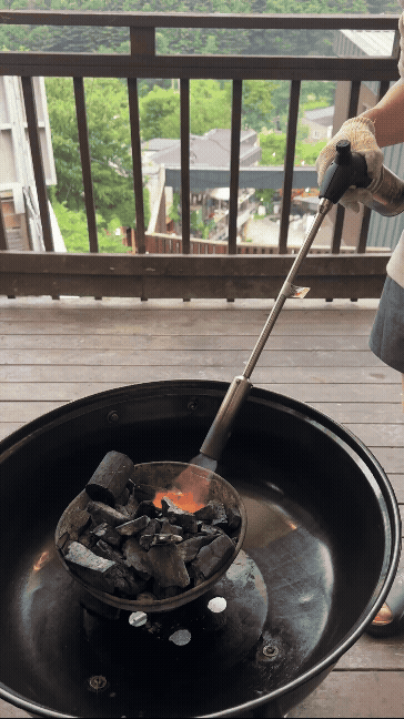 토치로 바베큐 숯에 불을 붙이는 모습