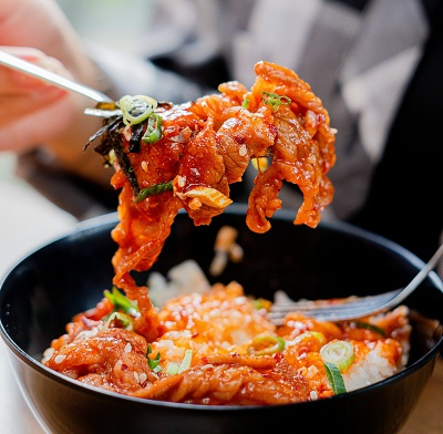 고추장으로 빨갛고 매콤하게 볶은 돼지고기를 숟가락으로 들어 올리고 있다 촉촉하게 윤기가 흘러 먹음직스러운 냉삼고추장볶음.