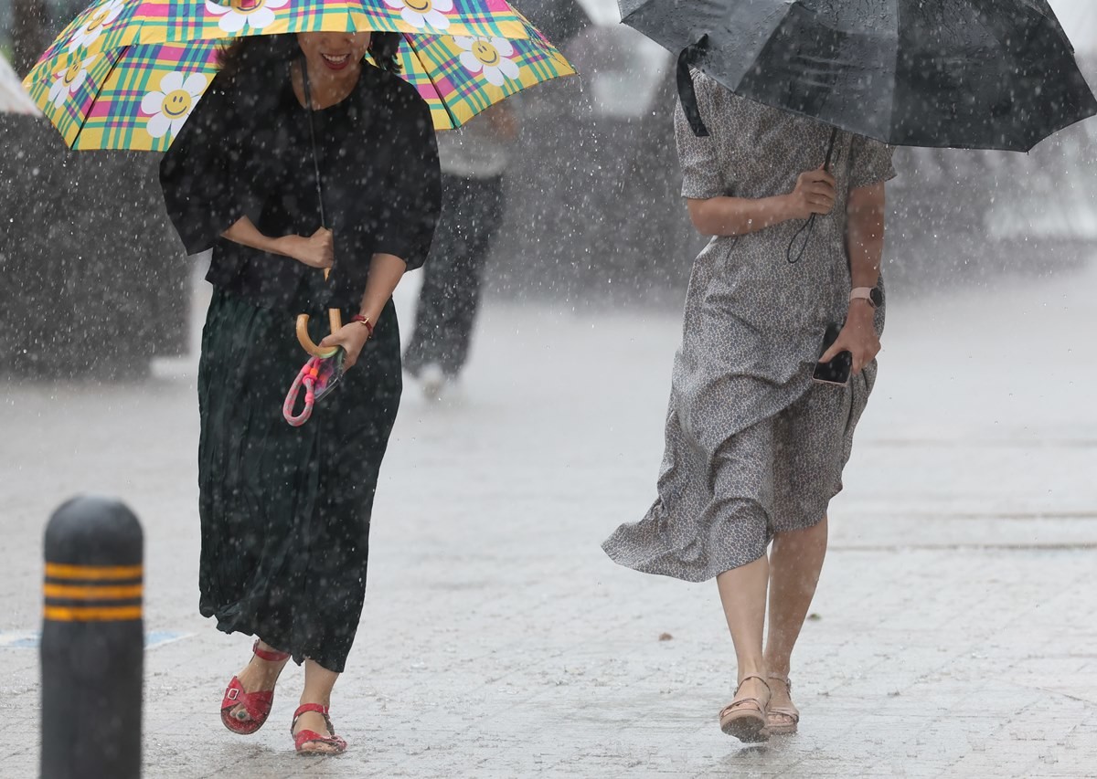 쏟아지는 비에 바쁘게 발걸음을 옮기는 시민들