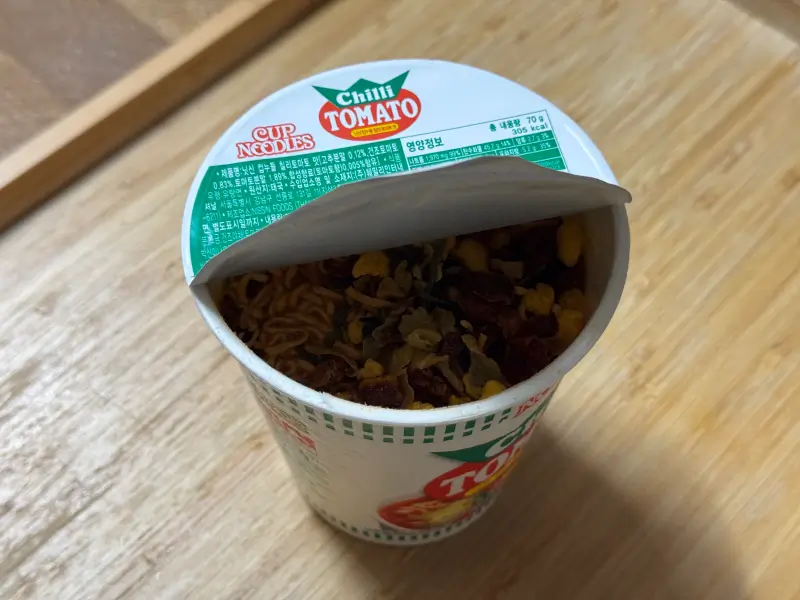 닛신 컵누들 칠리 토마토 맛 뚜껑 반쯤 열린 사진