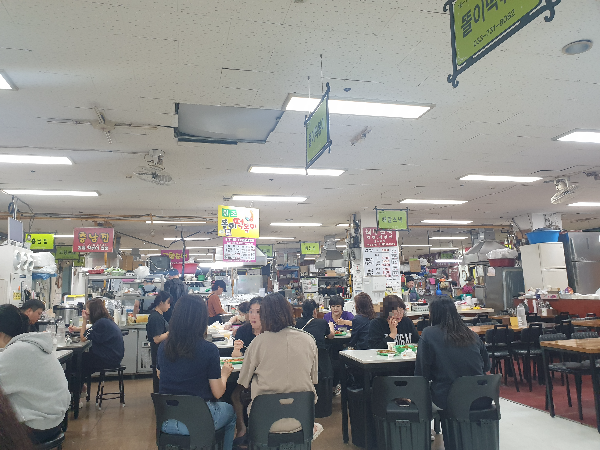 테이블 좌석에 손님으로 가득한 똘이 떡볶이. 그 옆집은 손님이 없다.