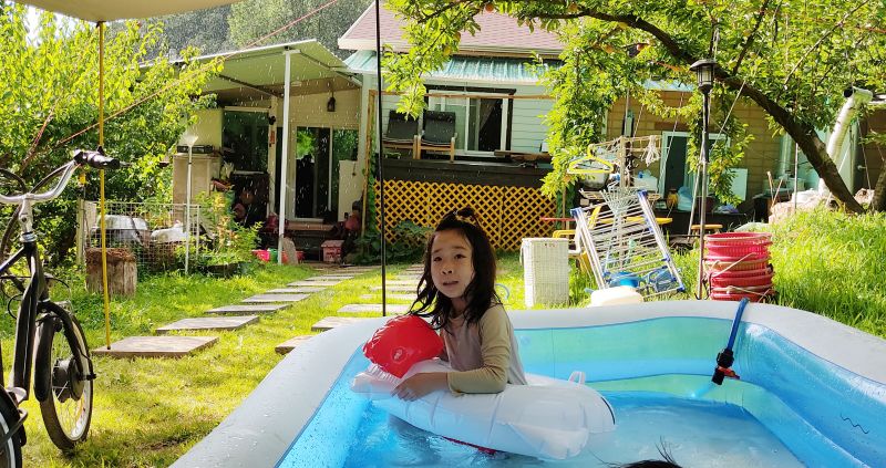 시골집 마당에 소나기가 오는데에도 수영장을 만들어 놀고 있는 사진 