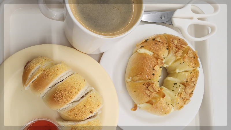 Assortment of homemade baked goods &mdash; bagel and sausage bread &mdash; served with hot coffee