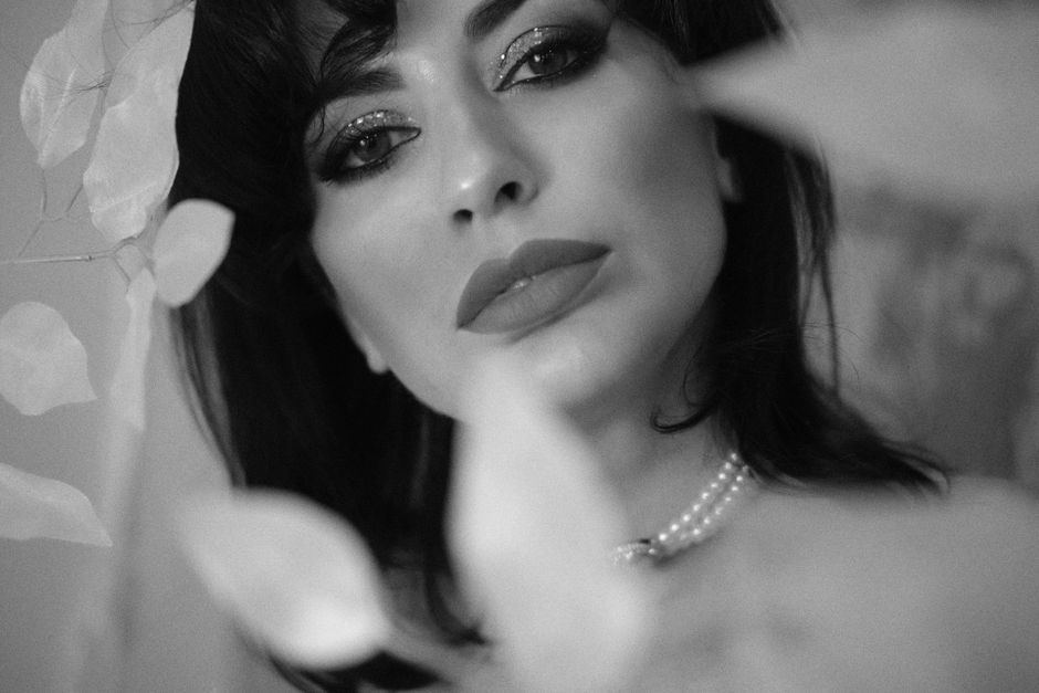 A glamorous black and white portrait of a woman with a pearl necklace and makeup.