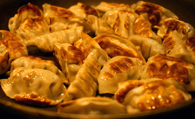 겉면이 노르스름하게 잘 구워진 군만두 20개가 프라이팬에 한가득 있다. 반달 모양이다.