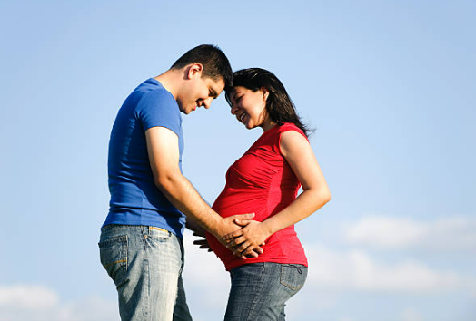 서로를 보며 활짝웃고있는 임신한 부부